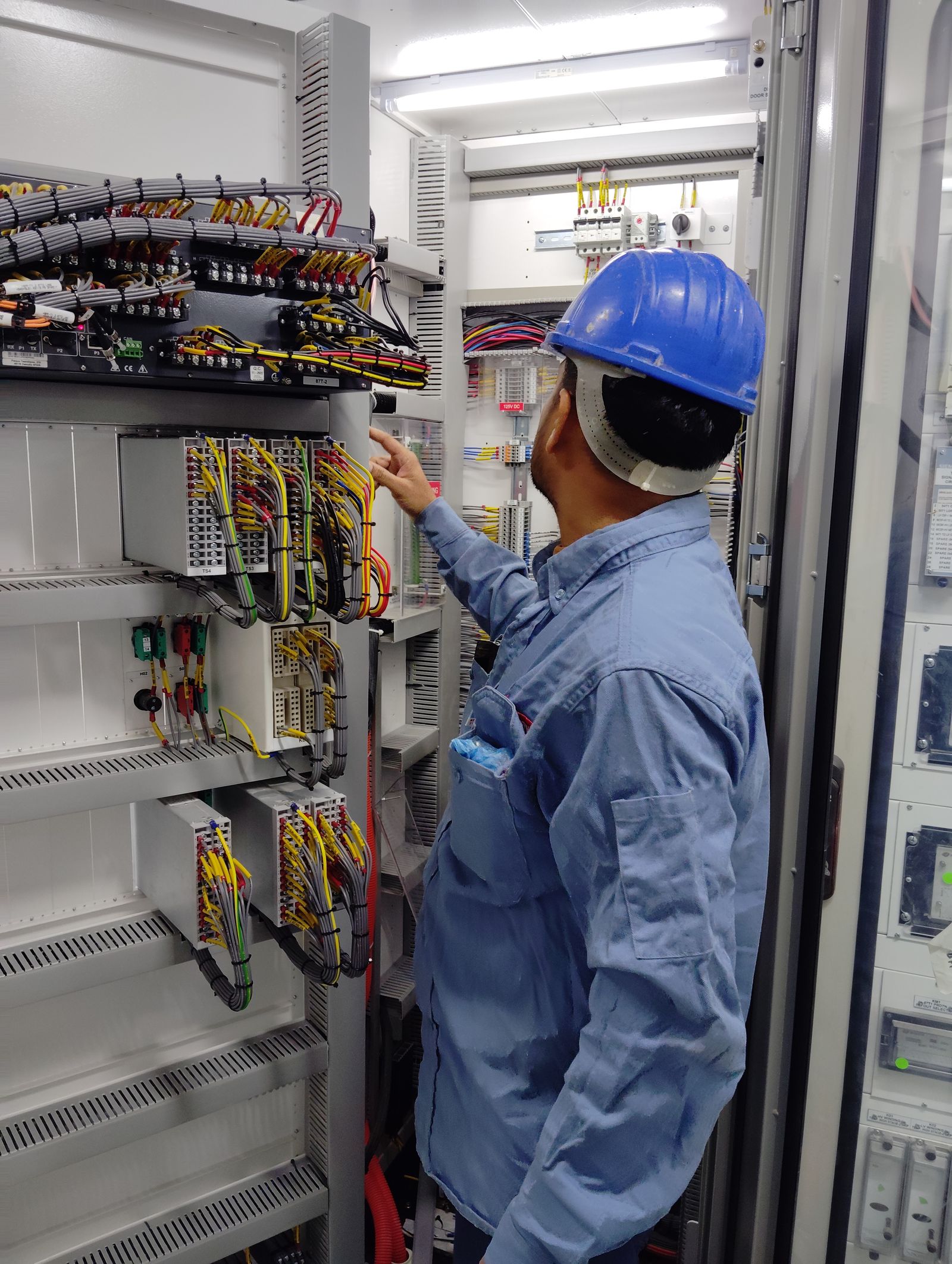 Engineer wiring PLC I/O modules inside an automation panel
