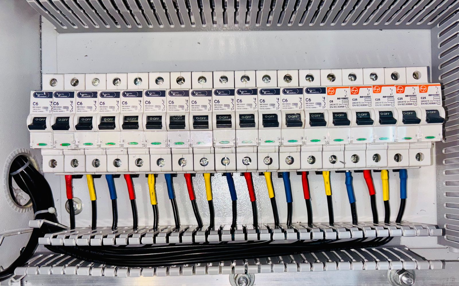 Circuit breaker row with colour-coded phase wiring in a protection panel